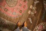 Distressed Oushak carpet with ruby red roundel edge, colorful floral motifs, and a mint green love bird.