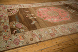 Distressed Oushak corner shows abrashed brown field, pink love bird, mint floral border.