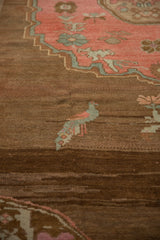 Distressed Oushak rug detail: blue and pink love bird on an abrashed chocolate brown field.
