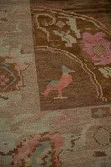 Distressed Oushak rug detail: love bird in ruby pink, mint blue on chocolate abrashed field.