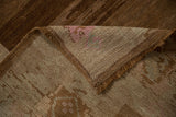 Distressed Oushak rug's hand-knotted foundation reveals pink and blue threads, sturdy brown fringe.