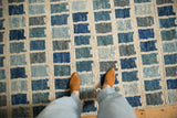Modern Afghani abstract geometric rug with varied blue, teal, and ivory squares underfoot.