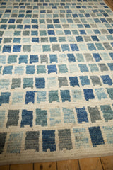 Modern abstract geometric pattern of ivory, blue, and silver blocks on the Afghani carpet.