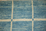 Close-up of Afghani modern geometric pattern, ivory lines, striated powder to sky blue pile.