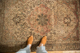 Vintage distressed Malayer rug's decorative wear and large terracotta medallion, shown from a high angle.