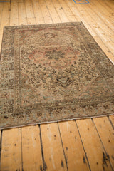 Angled full-length view of a distressed vintage Malayer rug showing its traditional pattern.