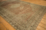 Angled view of an antique Bijar rug showing the corner design, Herati field, and time-softened wear.