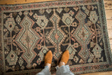 Distressed vintage Hamadan rug with geometric charcoal, melon, and ivory patterns.