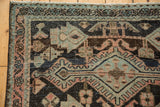 Distressed vintage Hamadan rug corner, revealing worn geometric patterns, foundation, and machine-bound side.