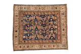 Antique distressed Caucasian square rug: navy geometric field, germinating plants, dusty blush starburst border.