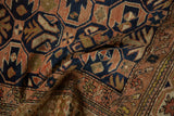 Distressed Caucasian rug pile with navy, dusty blush, and gold geometric starburst motifs.