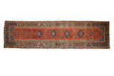 Antique Northwest Persian rug runner with concentric sapphire blue diamond medallions on a brick red field.