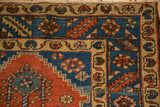 Sharp serrated leaf and floral motifs in the sapphire blue main border of an antique Persian runner.