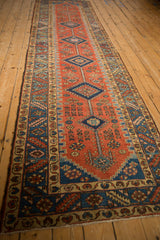 An angled view down the length of an antique Persian runner with concentric diamond medallions.