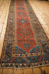 An antique Persian runner's column of diamond medallions shown at a long perspective angle.