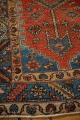 Close-up of the serrated leaf border in camel, blue, and red on an antique Persian runner.