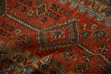 A detailed view of the antique Persian rug's textured pile in brick red, sapphire, and powder blue.
