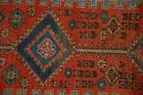 Sapphire blue diamond medallion and floral motifs on the brick red field of an antique Persian runner.