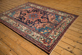 The intricate floral corner spandrels of a vintage Bakhtiari rug seen from a side angle.