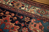 Intricate vines and blossoms on the navy field and sand border of a vintage Bakhtiari rug.