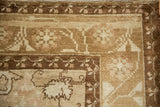 Corner detail of distressed vintage Kars carpet, highlighting beige floral sprays and serrated leaves.