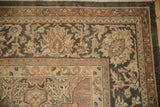 Distressed Sparta rug corner featuring multi-layered faded red borders and charcoal leaf motifs.