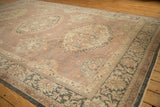 Distressed Sparta carpet's faded madder red field, leafy vines, and patterned border.