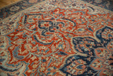 Angled view showing the even wear and scrolling vine motif on a distressed Ahar carpet.