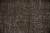 A scattered serpent element embroidered in ivory on the dark brown, textured Kilim weave.