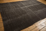 Angled view of a vintage Turkish kilim showing its dark brown and silver abrash texture.