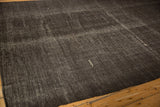 A single ivory embroidered serpent motif on the textured dark brown vintage Kilim.