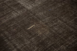 An ivory embroidered serpent motif on the dark brown, abrash-textured kilim weave.
