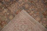 Distressed Tabriz carpet corner showing slate blue Herati pattern and hand-knotted foundation.