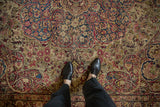 Detailed view of an antique Kerman carpet's low pile, revealing intricate floral vines and time-softened colors.