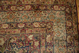 Corner spandrel of an antique Kerman carpet showing floral borders with buds and scrolling vines.