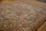 Low angle view across the antique Kerman carpet's scrolling floral field and time-softened colors.