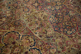 Close-up of an antique Kerman showing exposed knot heads amidst scrolling floral vines in red and blue.