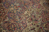 Antique Kerman carpet detail showing areas of wear to the knot heads amid floral arabesques.