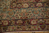 Low pile and visible knot heads on the floral arabesque border of an antique Kerman carpet.