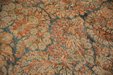 Worn floral pattern of the vintage Sarouk carpet, featuring dark blue, brick red, and ivory hues.