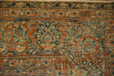 Worn hand-knotted texture with dark blue and red floral motifs on Sarouk rug.