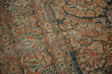 Distressed Sarouk carpet with worn floral motifs in denim blue, cherry red, and ivory.