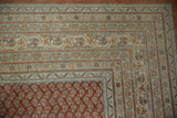 Distressed Mir Sarouk carpet corner with intricate red and blue borders and boteh field.