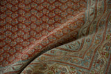 Distressed vintage Mir Sarouk carpet detail, showing brick red boteh field and patterned blue border.