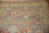 Close-up of distressed Mahal carpet corner, showing worn dusty blue and ruby red floral motifs.