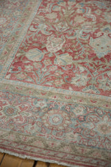 Distressed Mahal carpet corner with worn ruby red and dusty blue floral motifs, foundation evident.