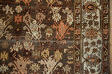 Detailed floral motifs on the abrashed charcoal field contrast with the lighter ivory border.