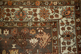 Intricate floral border in ivory and red next to the distressed charcoal field of a Persian rug.