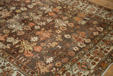 Corner view of a vintage Malayer rug showing its distressed pile, charcoal field, and floral border.