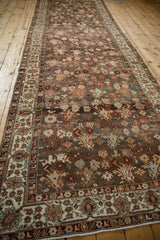 High angle view of a distressed Malayer runner with an allover botanical pattern on a dark field.